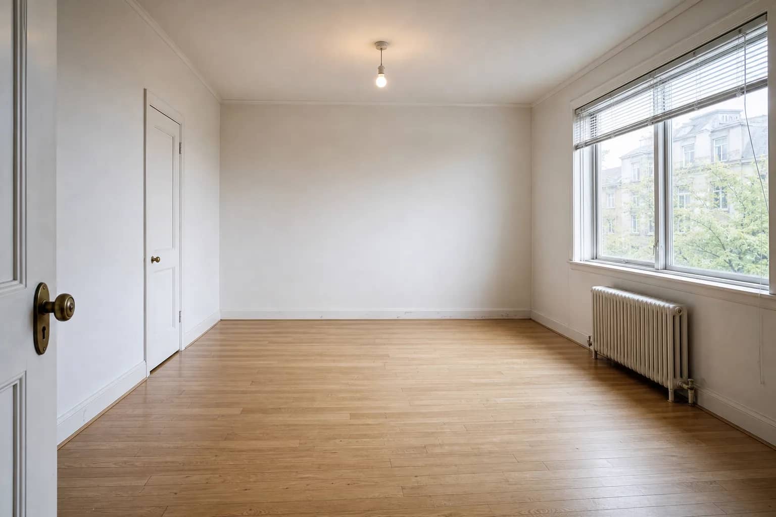 Wohnzimmer vor dem Home Staging — leerer Raum mit Holzboden und nacktem Heizkörper