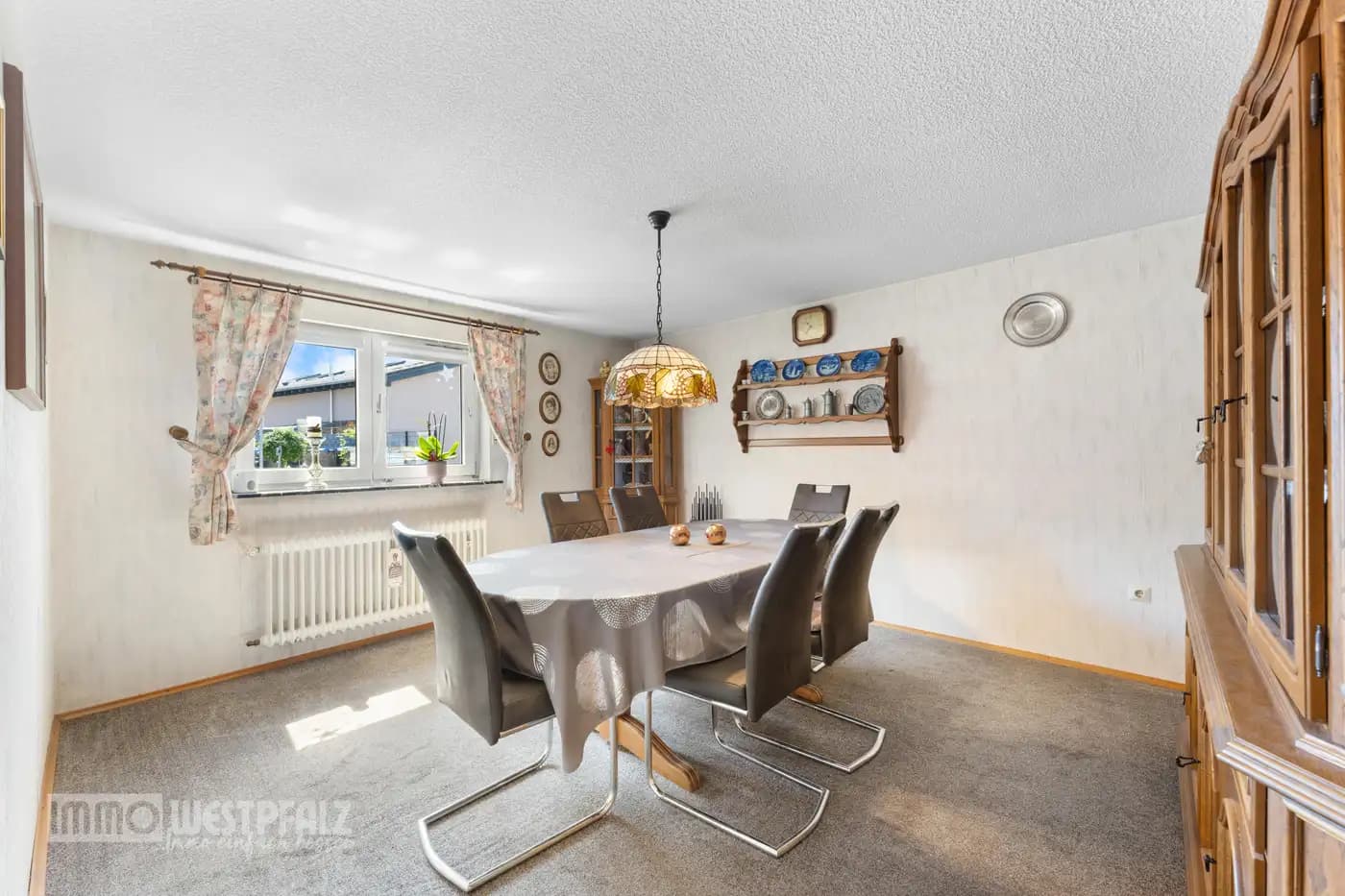 Helles Esszimmer mit modernem Esstisch, grauen Stühlen und Tiffany-Pendelleuchte — authentische Innenaufnahme für die Immobilienvermarktung.