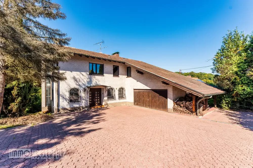 Außenansicht eines zweistöckigen Hauses mit großer gepflasterter Einfahrt, Ziegeldach und geschmiedeten Fenstergittern — professionelle Immobilienfotografie.