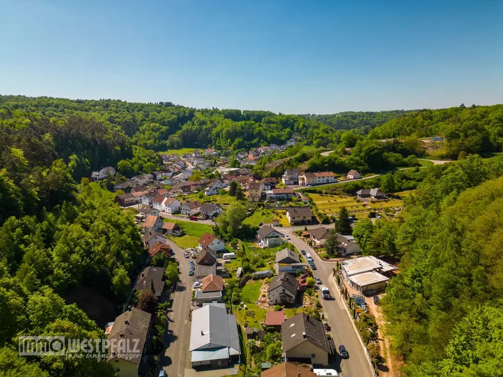 Aufnahme aus der Vogelperspektive eines Einfamilienhauses mit Terrasse und gepflegtem Garten.